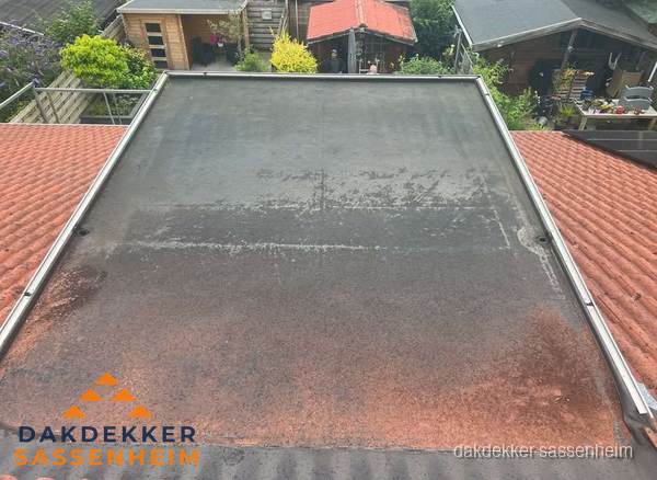 Verouderd plat dak met slijtage tussen schuine daken in Sassenheim Verouderd plat dak met slijtage tussen schuine daken in Sassenheim
