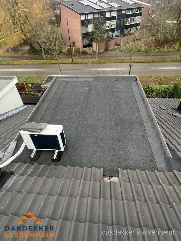 Plat dak inspectie met bitumen bedekking naast schuin pannendak in Sassenheim