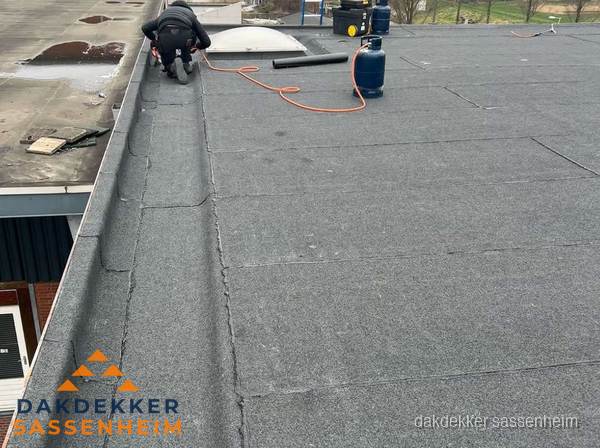 Dakdekker repareert bitumen dakbedekking op groot plat dak in Sassenheim
