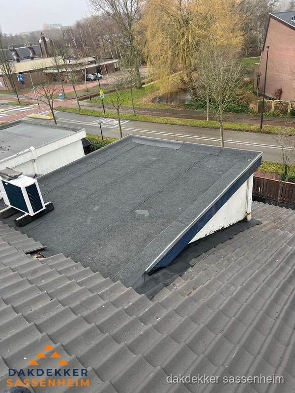 Plat dak met bitumen dakbedekking naast schuin pannendak in Sassenheim
