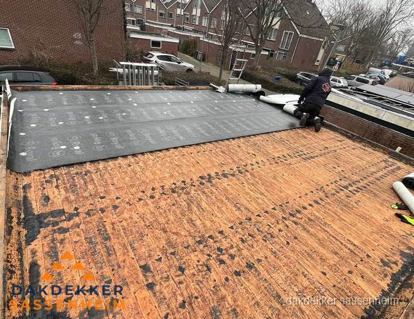 Dakdekker legt onderlaag op plat dak met houten constructie in Sassenheim