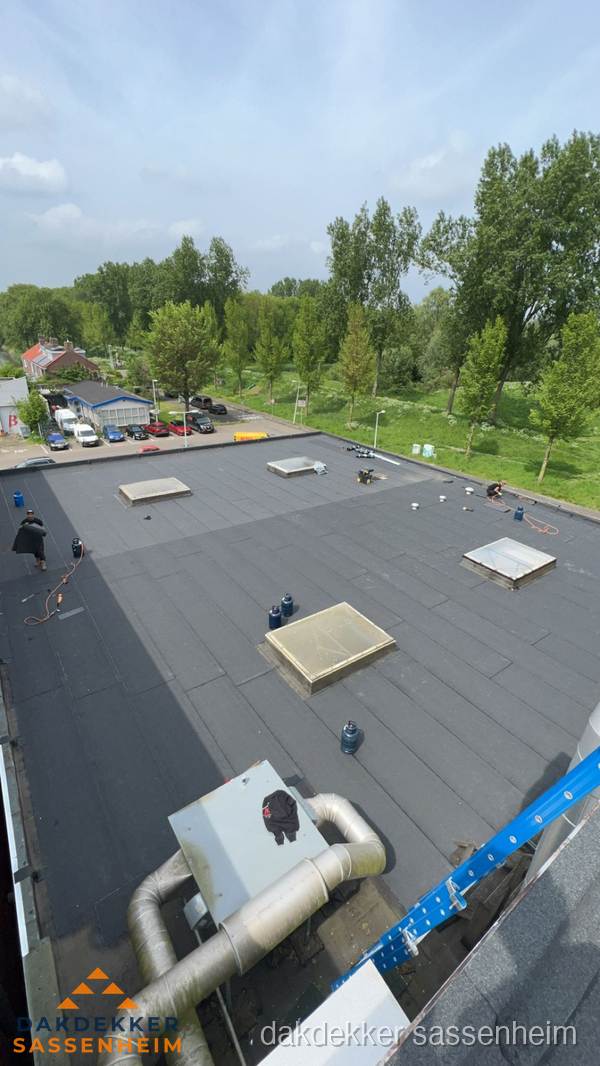 Dakdekker aan het werk op groot plat dak met bitumen in Sassenheim